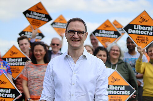Ian Sollom, Lib Dem Parliamentary Candidate for St Neots and Mid Camb, standing in front of campaigners. Ian is in the foreground while the campaigners are behind him, slightly out of focus so that Ian is highlighted.